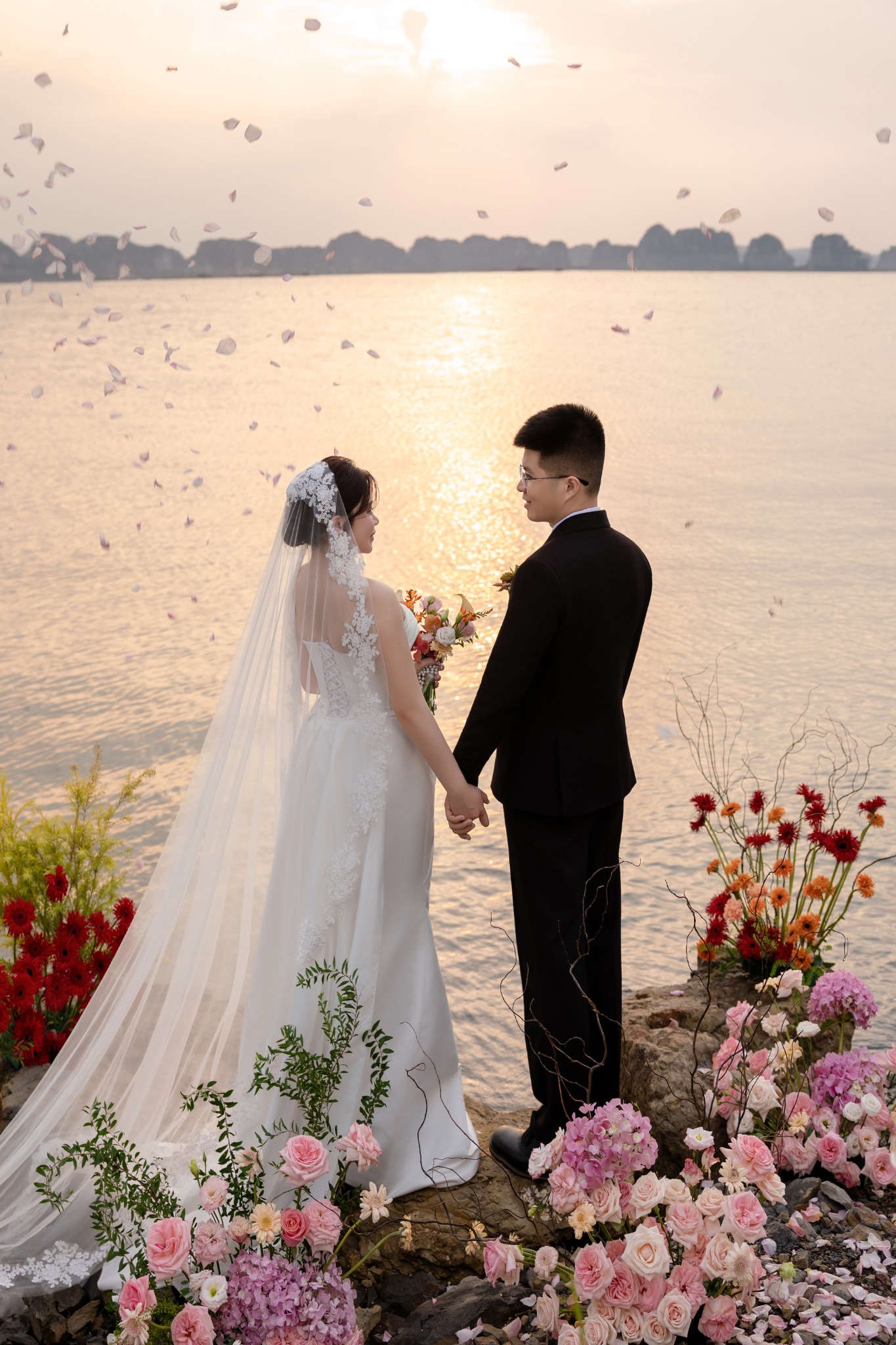 Cô dâu chú rể nắm tay dưới cánh hoa bay